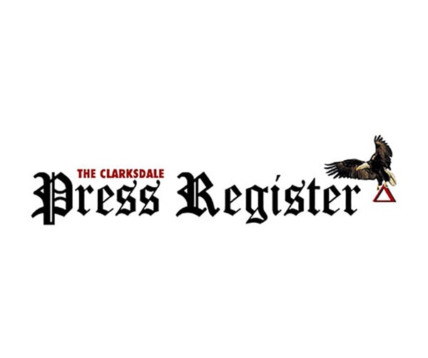 Logo for The Clarksdale Press Register with the name in black gothic lettering, The Clarksdale in red above Press, and an eagle holding a red triangle above the word Register.